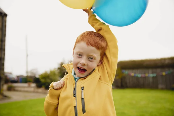 Маленький Хлопчик Дивиться Камеру Тримаючи Дві Жовті Кульки Одну Блакитну — стокове фото