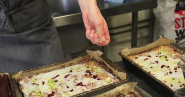 女厨师将压碎的开心果洒在她的开心果蛋糕上 — 图库视频影像