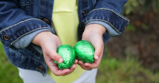 Panorering Skott Liten Flicka Håller Vissa Folie Förpackade Choklad Påskägg — Stockvideo