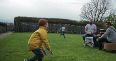 Dışında bir arka bahçede oynarken iki genç erkek. Bir tenis topu birbirine atıyor ve Velcro eldiveni ile yakalamak.