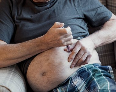Senior man with diabetes is injecting insulin into his belly at home.  clipart