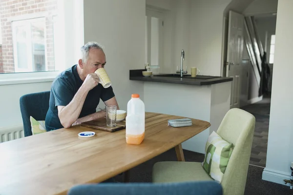 Hombre Mayor Está Sentado Mesa Comedor Casa Disfrutando Gachas Para —  Fotos de Stock