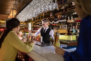 Bardaki kokteylden kokteyl yapan genç barmen..