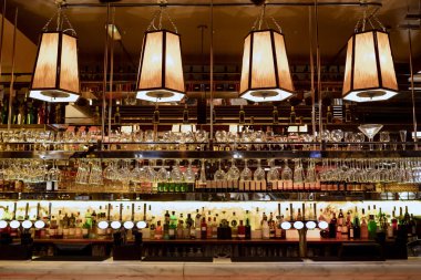 Barın iç tarafındaki bir restoranın geniş açılı görüntüsü ve barın arkasındaki raflar alkolle dolu..