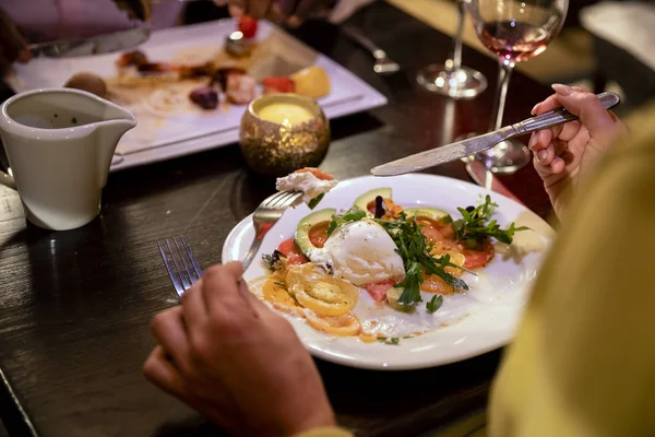 一个无法辨认的人在餐厅坐下时吃鳄梨和马苏雷拉沙拉的肩膀上 — 图库照片