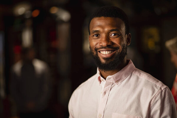 Headshot of a mid adult man smiling and looking at the camera.
