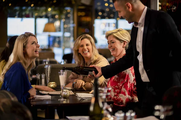 Mature Waiter Pouring Glass Prosecco Table Three Mature Women Sitting — Stock Photo, Image