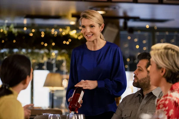 Female Waitress Reccomending Bottle Wine Two Couples While Sitting Restaurant — Stock Photo, Image