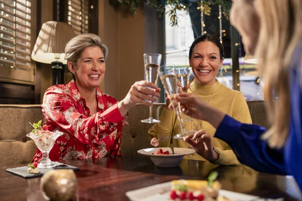 一小群成熟的女性朋友坐在餐馆的桌旁做庆祝敬酒 — 图库照片