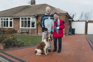 Üst düzey bir çift ve onların evde beslenen hayvan köpek evlerinin ön bahçedeki portre.