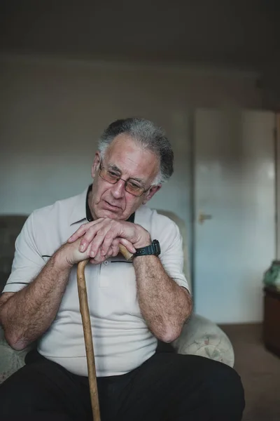 Starszy Mężczyzna Wygląda Smutno Głową Spoczywającą Lasce Salonie Swojego Domu — Zdjęcie stockowe