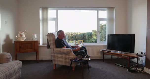 Senior Diabetesman Ontspannen Woonkamer Van Zijn Huis Met Een Boek — Stockvideo