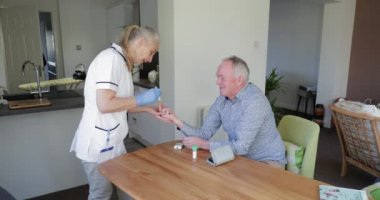 Üst düzey diyabetik adam bir onay evde bir bölge hemşire partisi. Onun kan şekeri kontrol ediyor. 