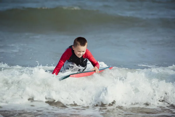 Mały chłopiec uderzając w surf — Zdjęcie stockowe