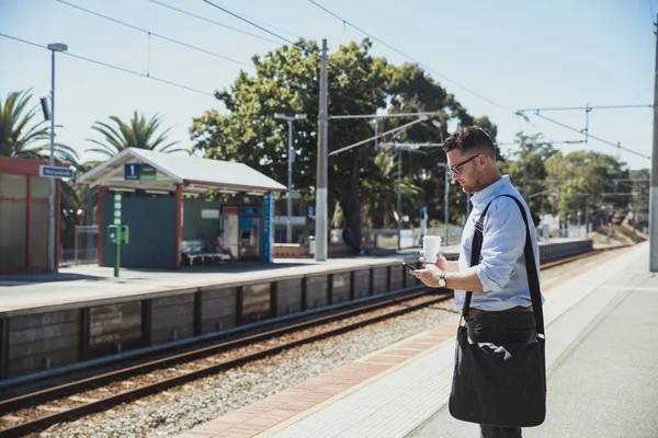Podnikatel, pomocí chytrého telefonu na vlakovém nádraží — Stock fotografie