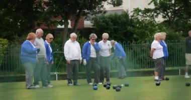Çimlerin üzerinde bowling oynayan bir grup son sınıf arkadaşının yan görüntüsü..