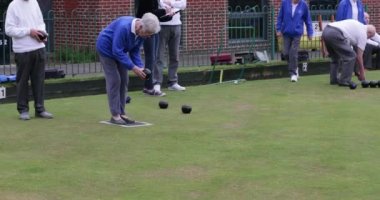 Bir grup son sınıf arkadaşının çim bowlingi oynarken ki yan görüntüsü. Son sınıf bir kadın şansını deniyor..