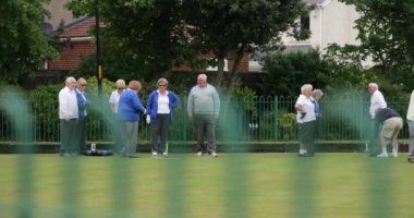 Çimlerin üzerinde bowling oynayan bir grup son sınıf arkadaşının yan görüntüsü..