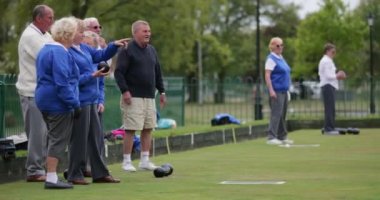 Bir grup son sınıf arkadaşının çim bowlingi oynarken ki yan görüntüsü. Son sınıf bir kadın şansını deniyor..