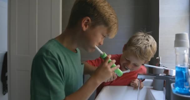 シンクで一緒に歯を磨く2人の若い男の子の側面図 — ストック動画