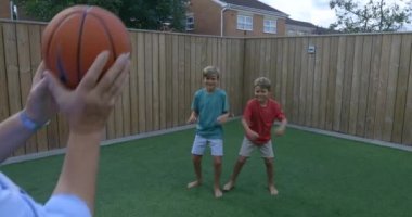 Arka bahçede bir basketbol topuyla oynayan bir aile fotoğrafı..