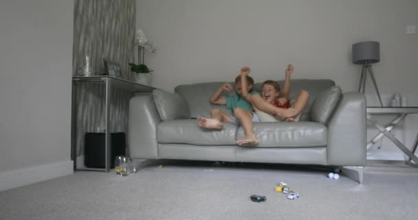 两个弟弟坐在沙发上看电视的镜头 他们穿着休闲装 — 图库视频影像