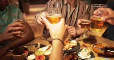 Bir grup erkek arkadaş birlikte yemek için dışarı çıktı. Kameralar masadaki yemeklerden, birlikte kutlama yapan adamlara kadar uzanıyor..