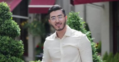 Asyalı bir adamın şarap içerken kameraya bakıp gülümsediği yakın çekim. Dışarıda bekliyor..