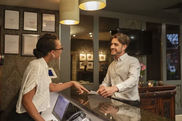 A hotel receptionist talking to a customer who is checking in to the hotel.