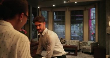 Otel resepsiyonisti, otele giriş yapan bir müşterinin bağlantısız ödemesini alıyor. Akıllı telefonuyla ödeme yapıyor..