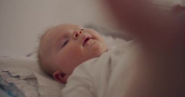 Bir anne, bebeğin temiz ve rahat olduğundan emin olmak için bebeğinin bezini değiştirme masasında dikkatlice değiştirir..