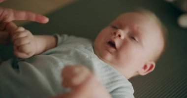 Bir anne, küçük oğluyla hasırın üstünde egzersiz yapar ve motor becerilerini geliştirmesine yardım eder..