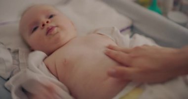Bir anne, yeni doğan karnına nazikçe masaj yapar. Hem de üzerini değiştirirken. Ebeveynlik ya da çocuk bakımı teması için birebirdir..