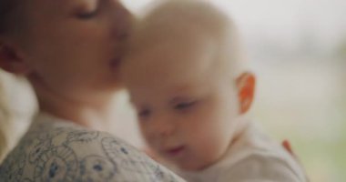 Şefkatli bir anne yeni doğmuş bebeğini kucaklar ve alnından öper. Minik bebek sevinçle gülümsüyor.