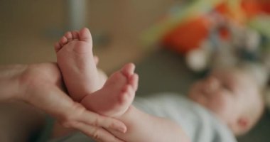 Neşeli bir anne, yeni doğmuş bebeğinin minik ayaklarına hayranlıkla bakarken saf mutluluğu ifade eder..