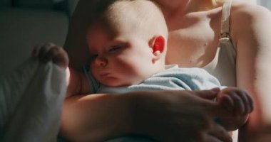 Anne tarafından sarılırken ve kucaklanırken bir bez tutan küçük bir bebeğin silueti..