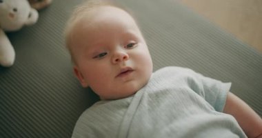 Mindere uzanmış sevimli, gülümseyen bir bebeğin yakın çekimi. Güzel, küçük bir yüzü var..