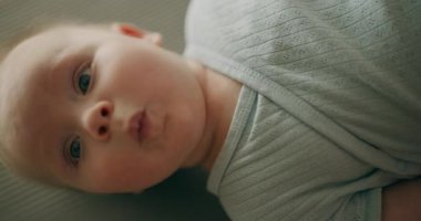 Bir erkek bebeğin yüzünün dikey yakın çekimi, detayları ve ifadeleri yakalıyor..