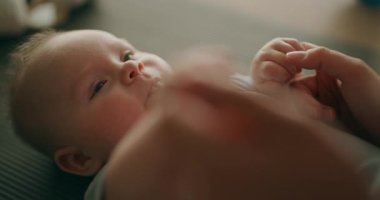 Annesiyle oynayan küçük bir bebeğin sevimli yakın çekimi. Anne, paspasın üzerinde oyun oynamaktan hoşlanan bebeklerin ellerini tutar..