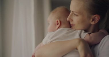 Bir annenin yeni doğan oğlunu sevgiyle kucakladığı huzurlu bir an, mutluluğu yansıtır..