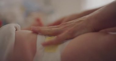 Küçük bir bebeğin göbek bölgesine nazikçe merhem süren bir ebeveynin yakın çekim görüntüleri..