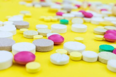 Çeşitli ilaç tıp hap, tablet ve kapsüller sarı arka plan üzerinde