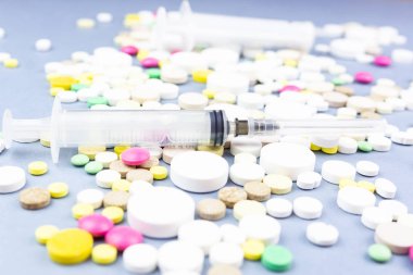 Çeşitli ilaç hapları, haplar ve kapsüller mavi arka planda.