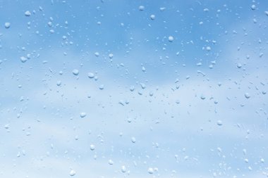 Bir bulutlu gökyüzü arka plan cam üstünde su damlaları. su doku camına