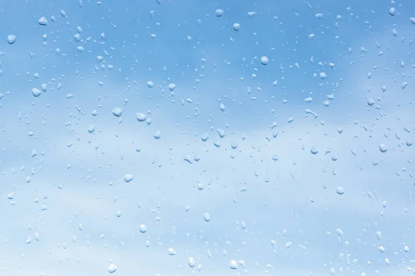 Drops of water on a glass against a cloudy sky background. water texture on the glass