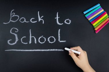 Çocuk tebeşir tahtaya kelime okul yazıyor.