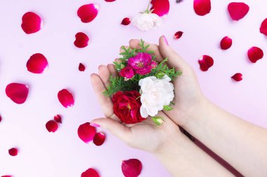 Çiçek ve çiçek yaprakları güzel parlak makyaj ve gül yaprakları ile el pembe arka plan üzerinde güzellik nazik eller