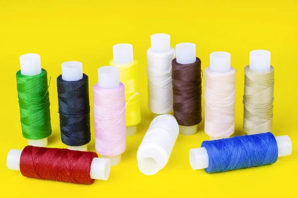multicolored spools of thread on a yellow background, sewing kit