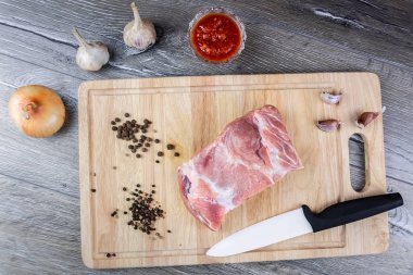 Çiğ taze et biftek domuz kiraz domates, acı biber, sarımsak, soğan bir kesme tahtası, gri bir arka plan üzerinde et üzerinde