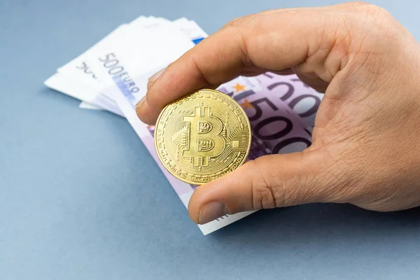 Beş yüz Euro banknot üzerinde gri bir arka plan arka plan üzerinde elinde Bitcoin